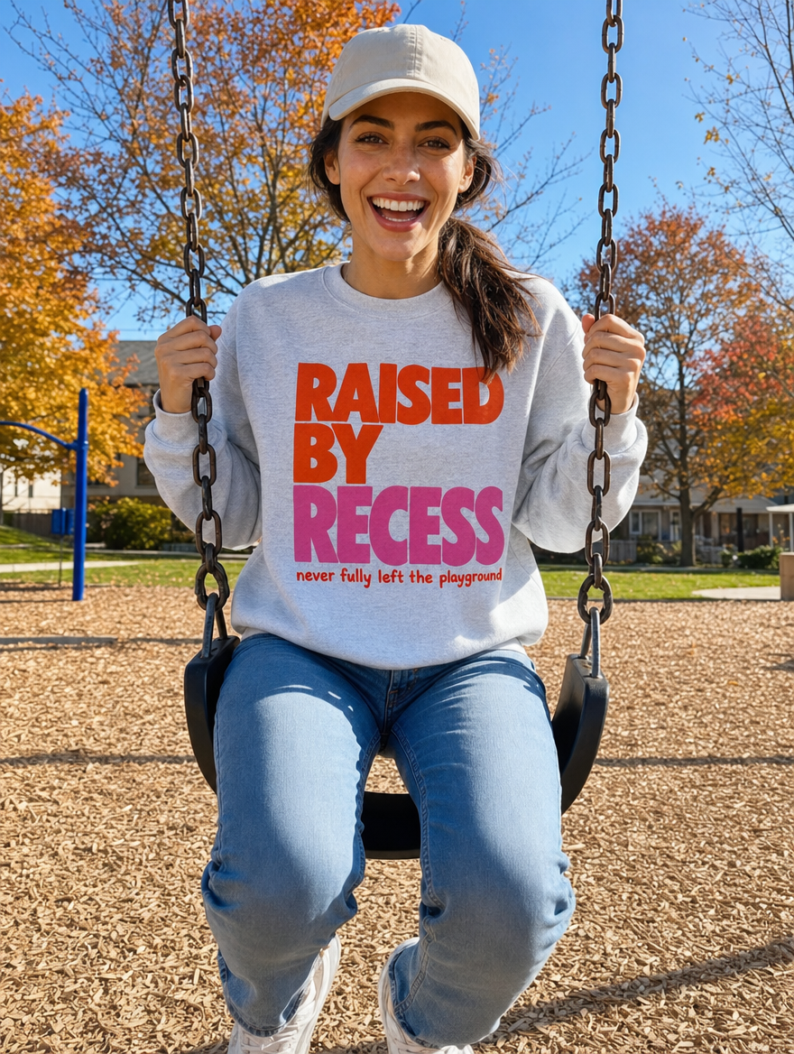 Woman on a playground swing in the Raised by Recess sweatshirt (AI-generated model)