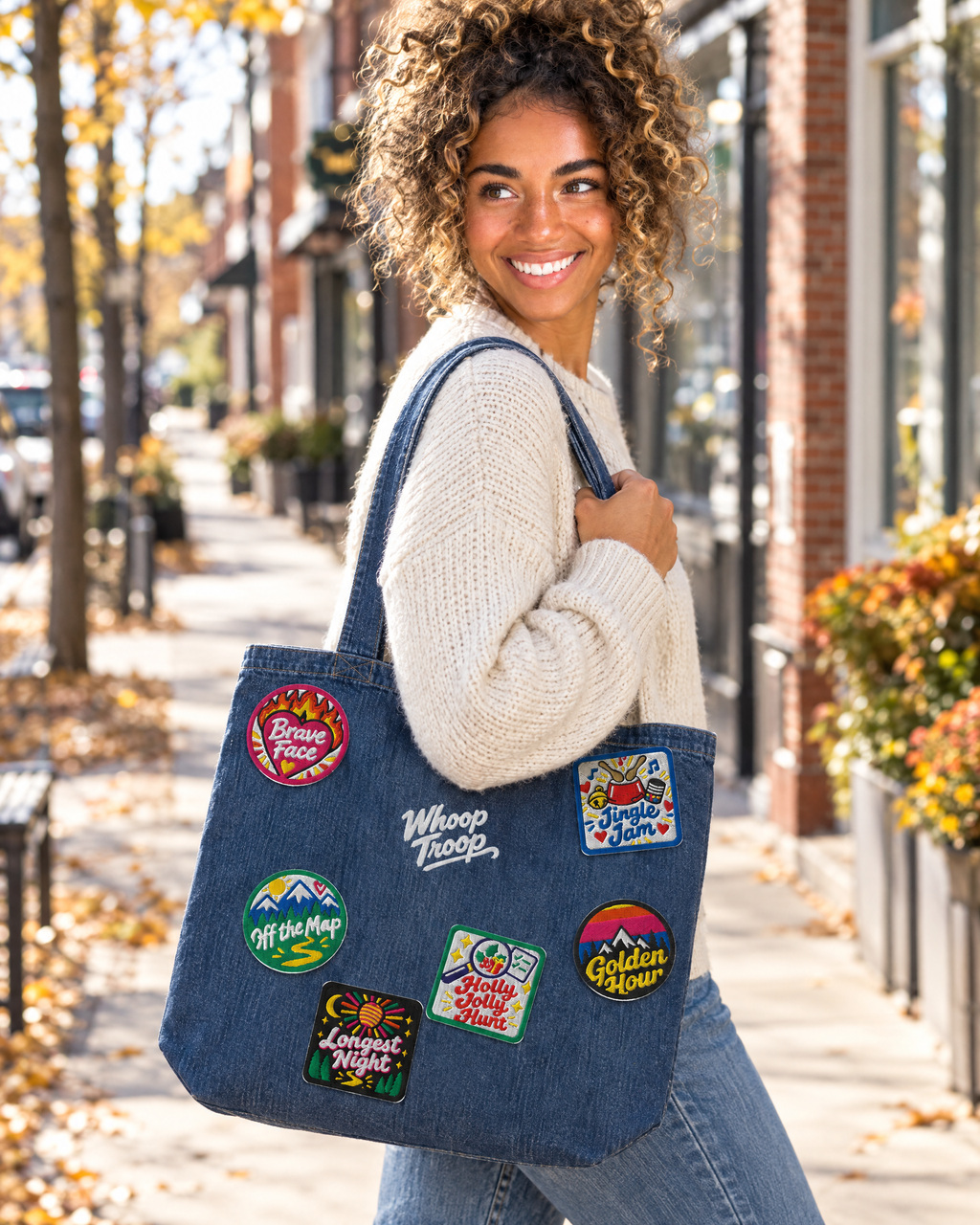 AI-generated image: a woman carrying the Whoop Troop denim tote covered in badges down a fall main street